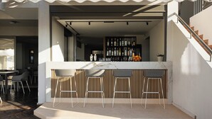 An outdoor bar area with a marble countertop, three bar stools, and a variety of bottles. - Bella Vista Hotel by Checkin (Hersonissos)