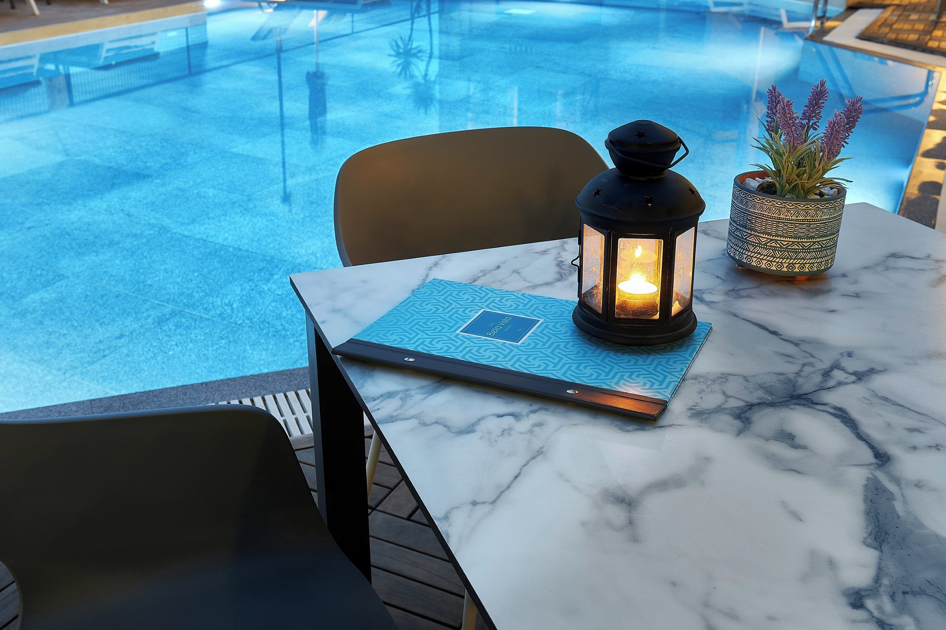 A marble table with a candle, a potted plant, and a menu.