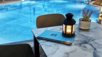 A marble table with a candle, a potted plant, and a menu.
