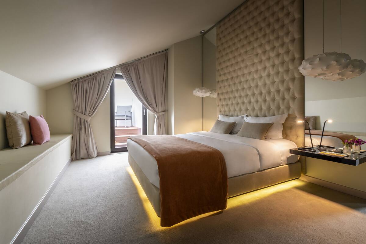 Un dormitorio moderno con una cama grande, una mesita de noche con lámpara y vistas al exterior.