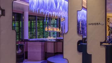 A bar area with a modern design, featuring a counter with various bottles and a sign that reads "WOOBAR".