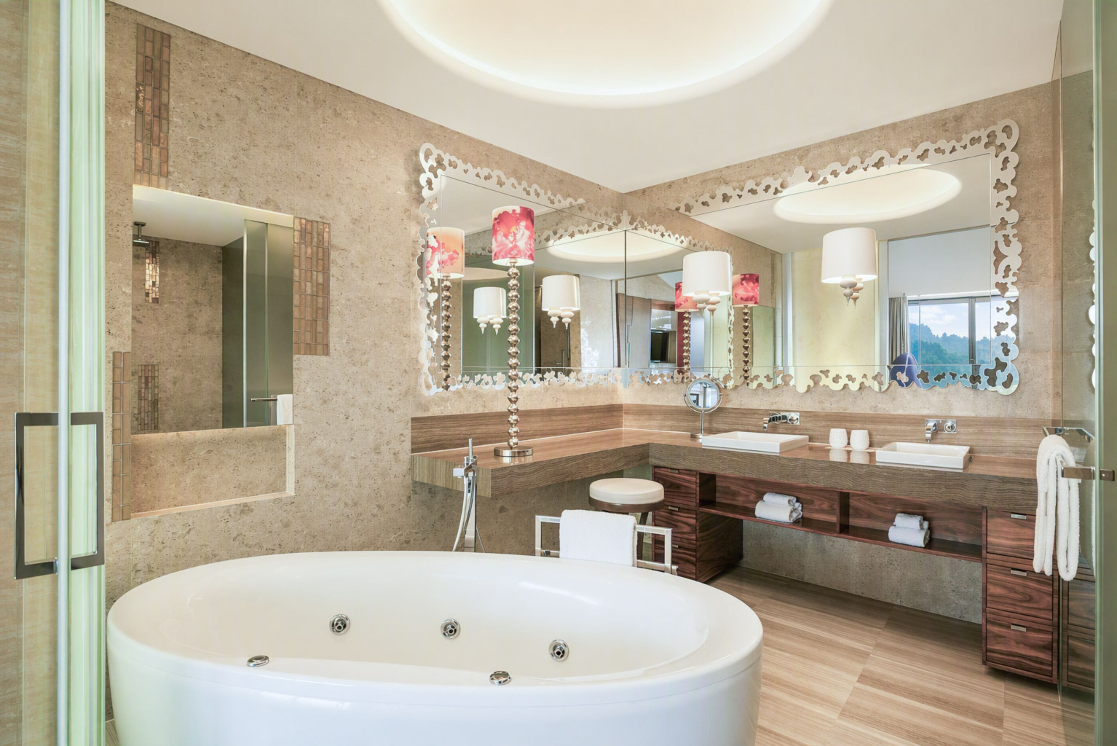 Un baño moderno con una bañera grande, dos lavamanos y un tocador con espejo.