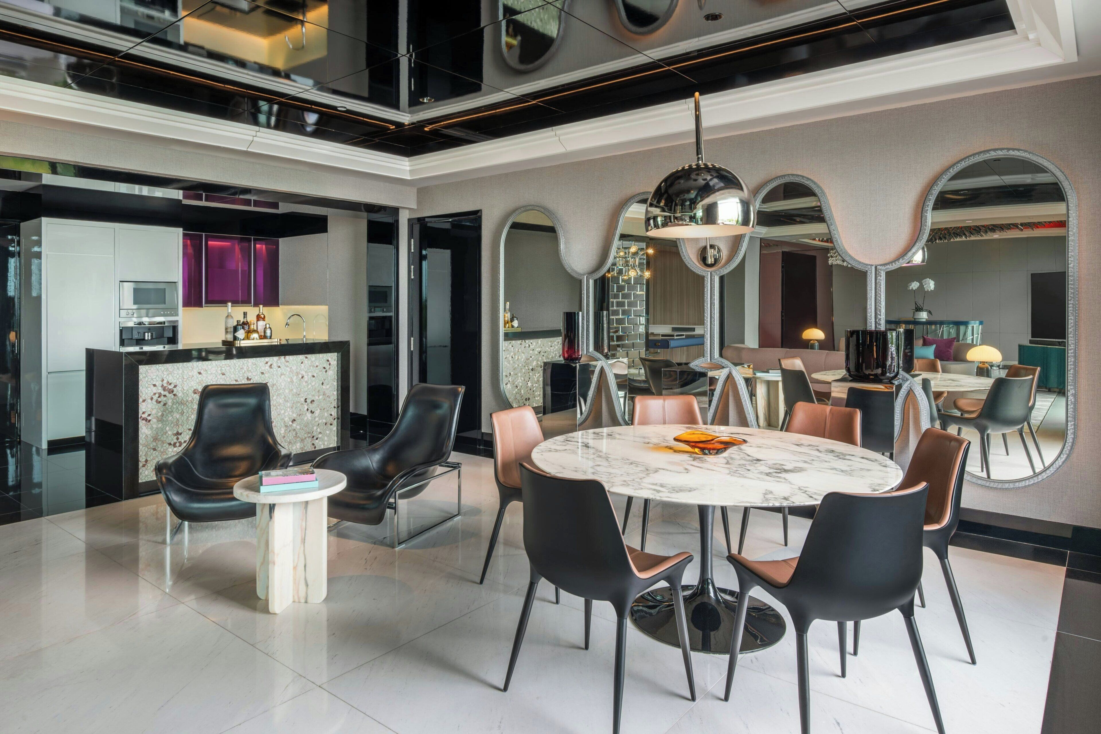 A modern dining area with a marble table, black and brown chairs, and a central chandelier.