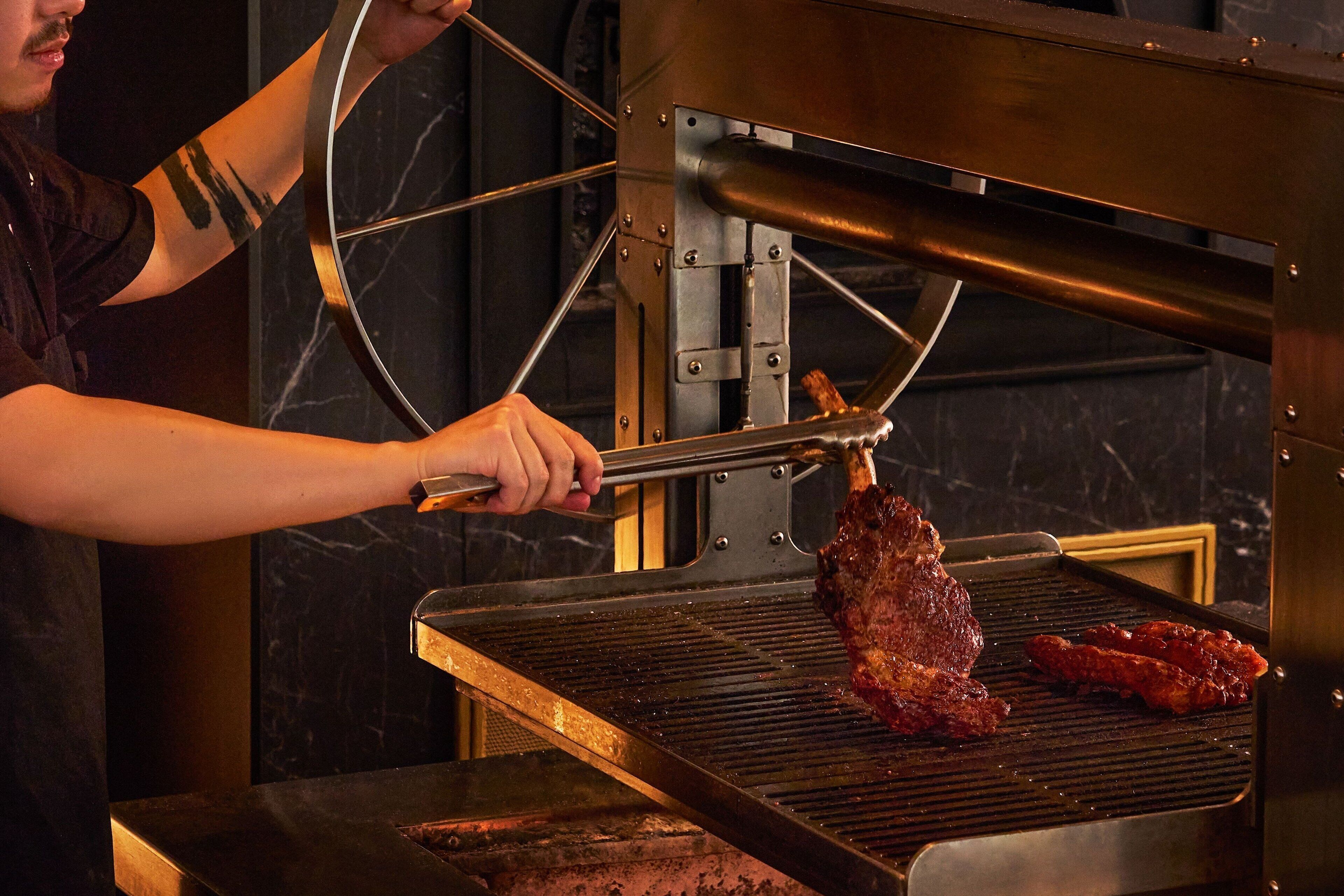 Una persona asando carne en una parrilla grande al aire libre.