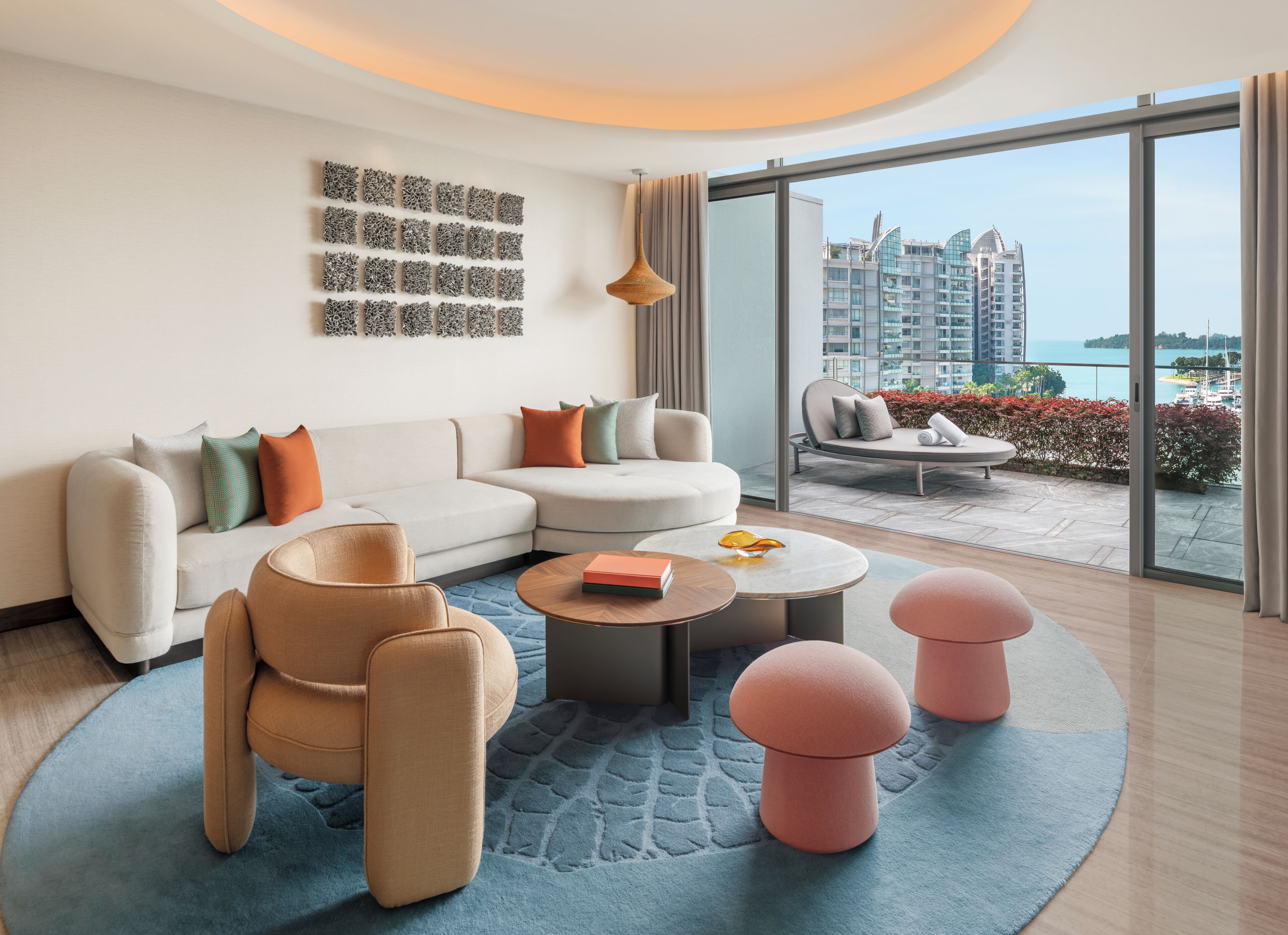 Una sala de estar moderna con un sofá, sillas, una mesa de centro y vistas de un paisaje urbano a través de grandes ventanales.