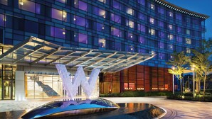 A modern hotel with a large illuminated 'W' sculpture in front, a glass atrium, and a well-lit facade. - W Singapore - Sentosa Cove (Newly Renovated) (Singapore)