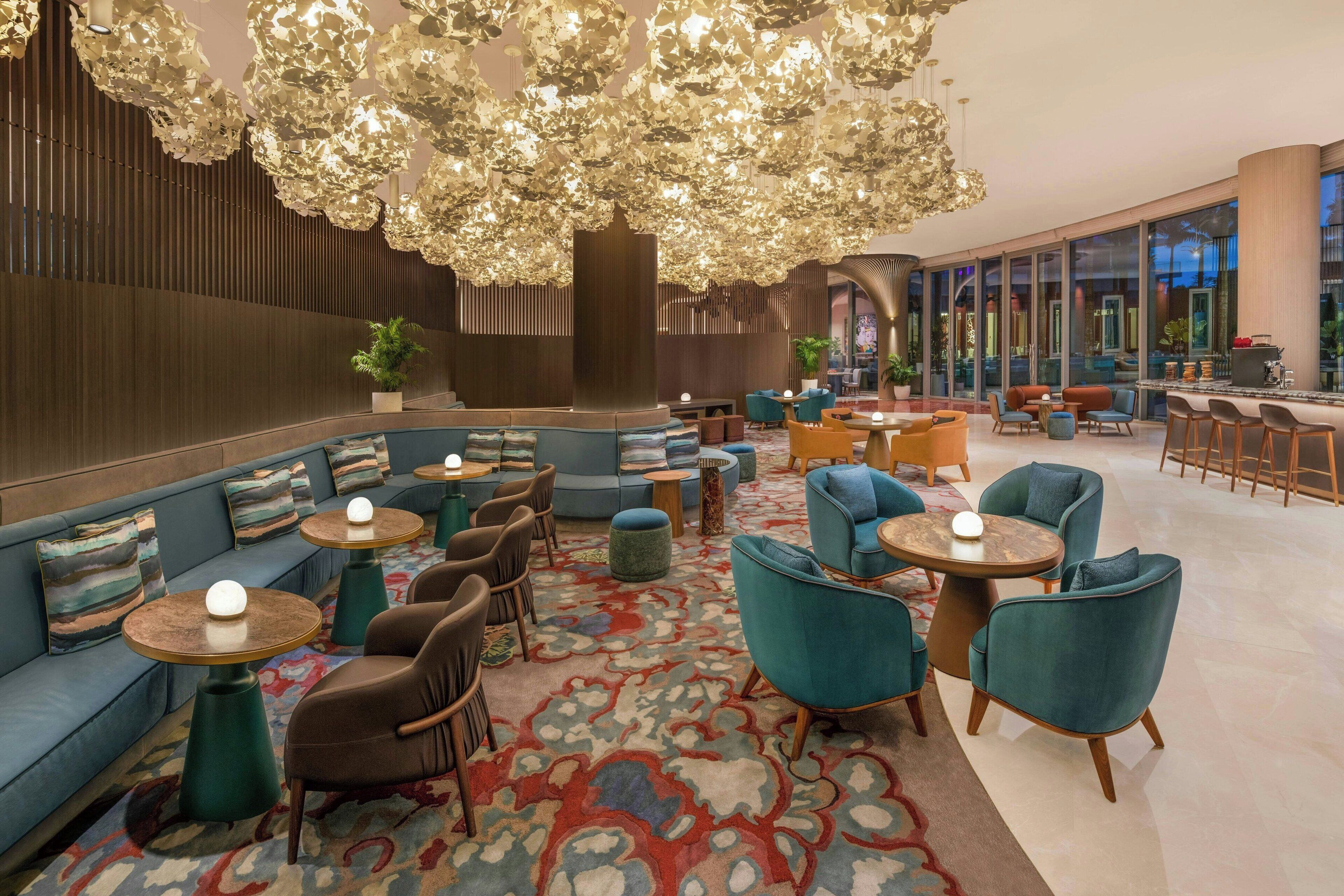Un espace de détente moderne, aménagé avec des coins salon comprenant des canapés et des fauteuils, ainsi qu’un bar doté de tabourets.