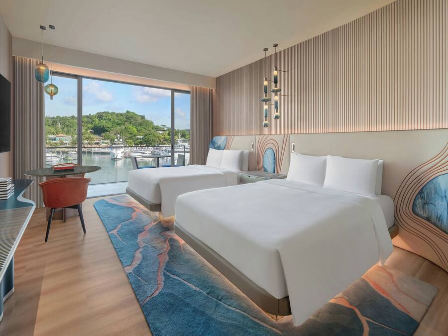 Een moderne hotelkamer met twee bedden, een televisie en uitzicht op een jachthaven.