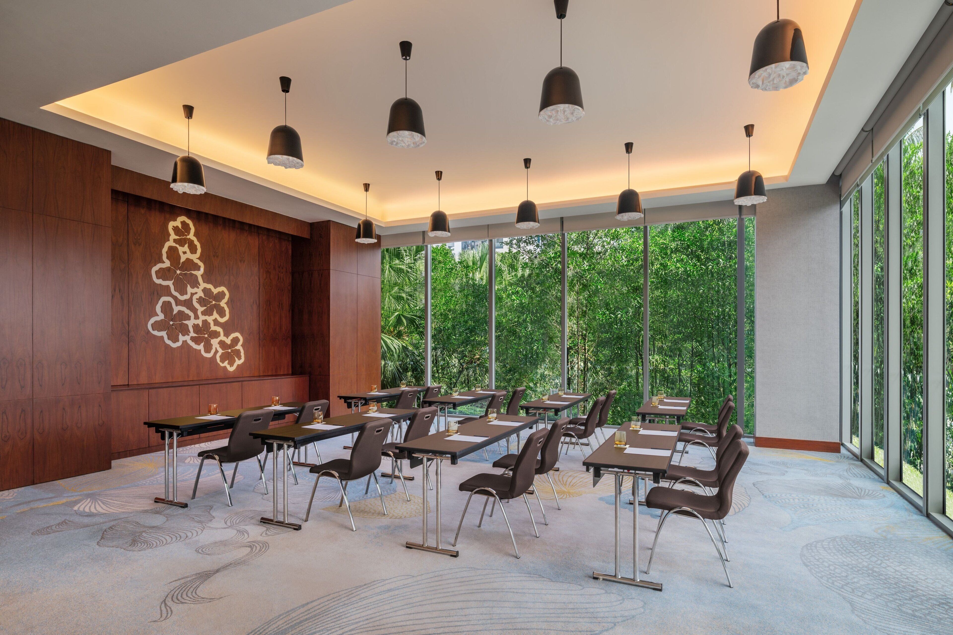 A conference room with tables and chairs, large windows, and pendant lighting.