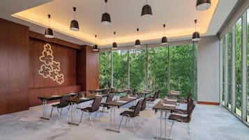 A conference room with tables and chairs, large windows, and pendant lighting.