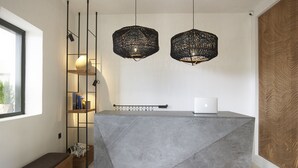 A reception desk with a modern design, a laptop on top, and two hanging pendant lights. - Bellonias Villas (Santorini)
