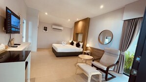 A modern hotel room with a bed, a desk, a chair, a small table, and a large mirror. - Evergreen Resort (Koh Samui)