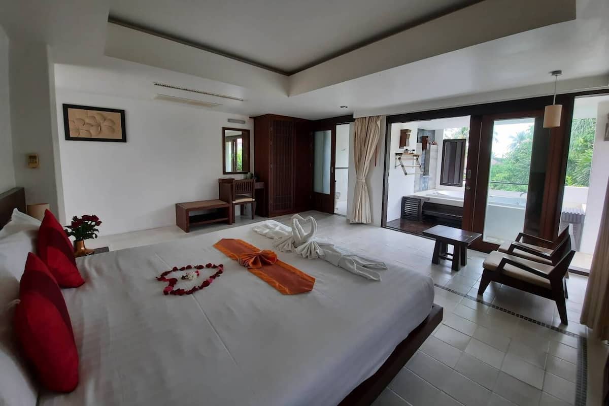 Habitación de hotel con una cama grande, escritorio, silla, armario y balcón con vistas.