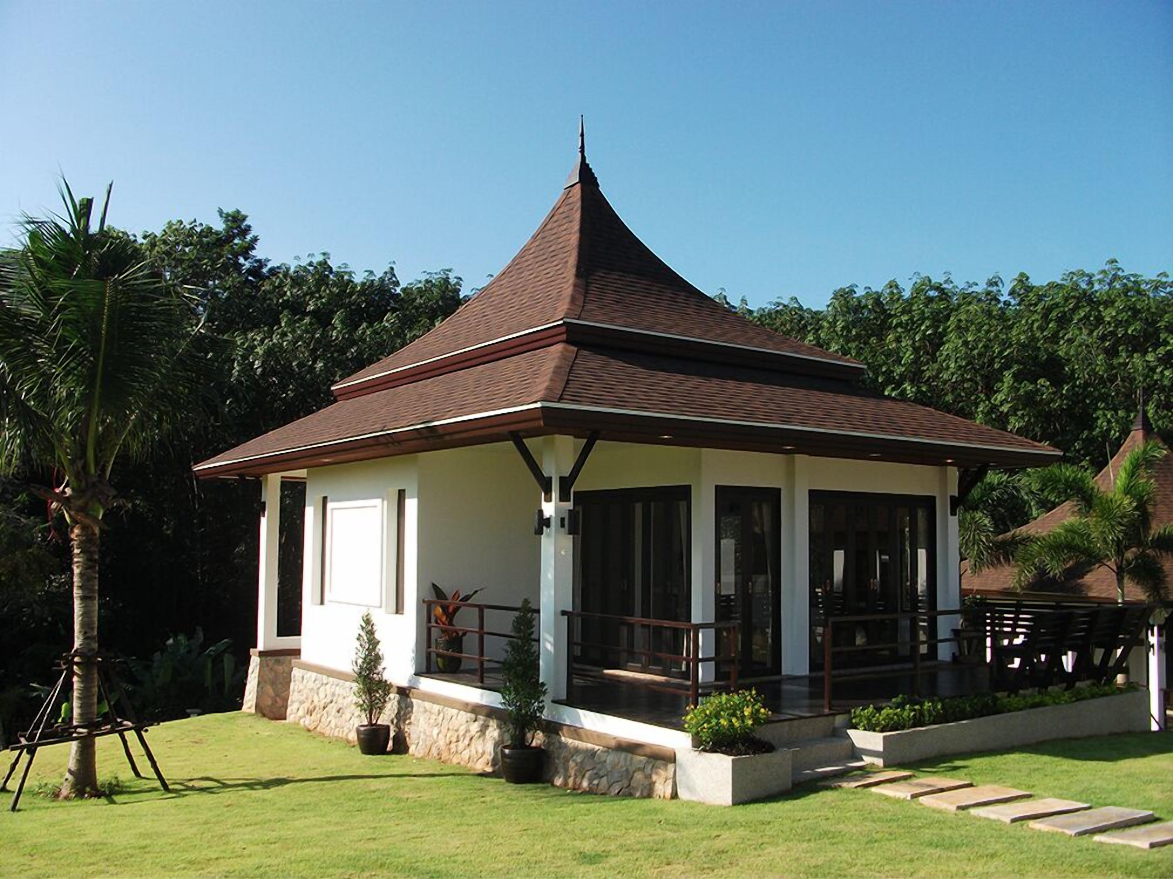A small, single-story building with a sloped roof, surrounded by a well-maintained lawn and potted plants.