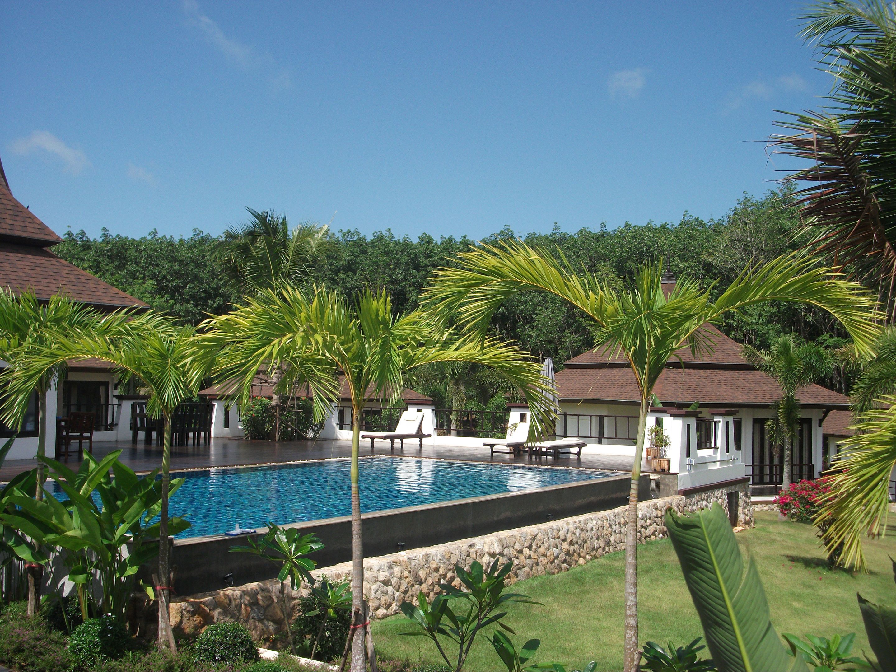 Een buitenzwembad, parasols bij het zwembad en ligstoelen