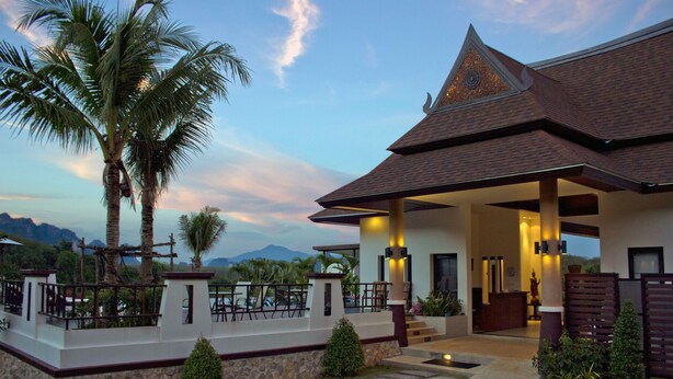 A modern house with a covered porch, stone walls, and a view of mountains. - Leelawadee Garden Resort (Krabi)
