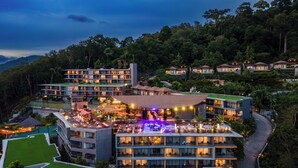 A modern hotel with multiple floors, outdoor seating areas, and a pool. - Kalima Resort & Spa, Phuket (Patong)