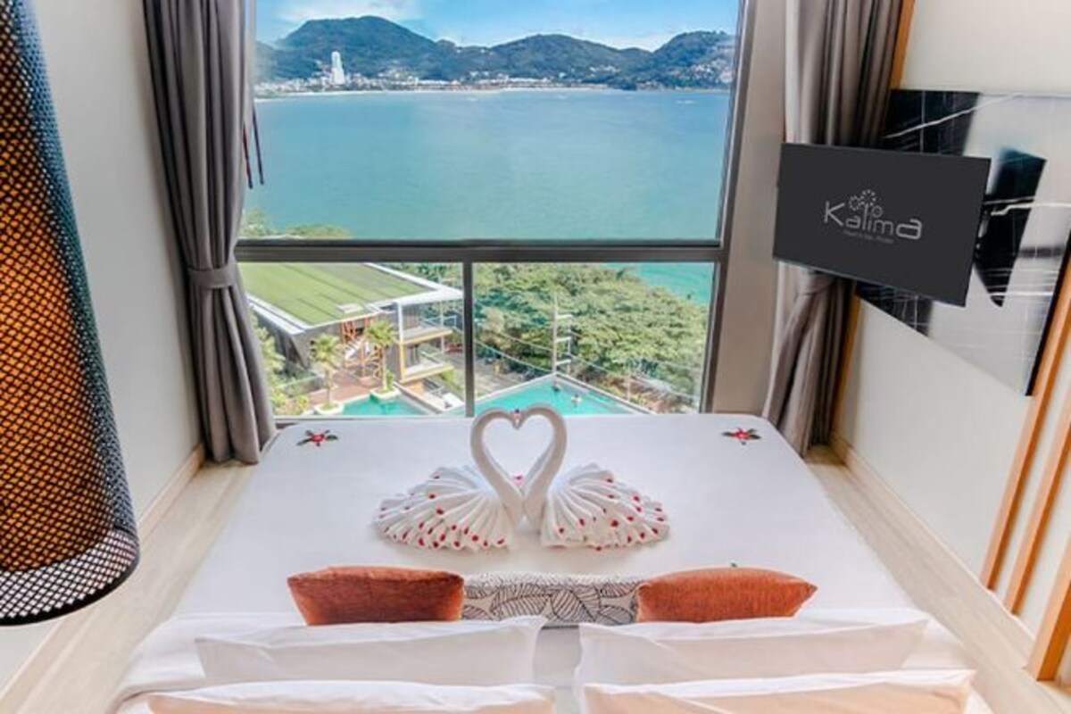 Una habitación de hotel con una cama, vista a un cuerpo de agua y un cartel en la pared.