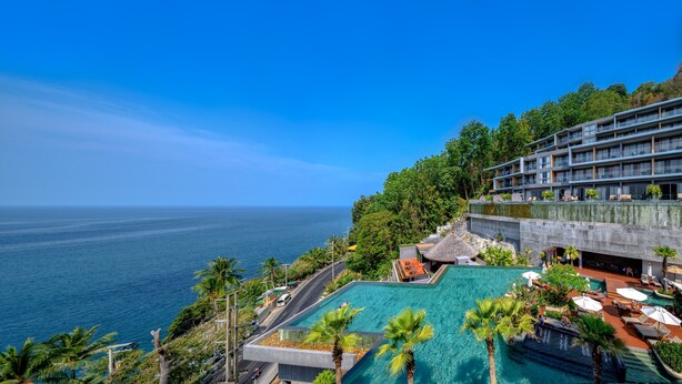 A resort with a large infinity pool, a view of the ocean, and a multi-story building with balconies. - Kalima Resort & Spa, Phuket (Patong)
