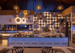 A modern restaurant with a central island, decorative wall panels, and hanging pendant lights. - Kalima Resort & Spa, Phuket (Patong)