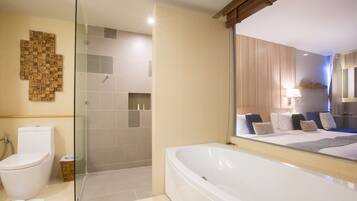 Un baño moderno con cabina de ducha de vidrio, una bañera grande y un inodoro.