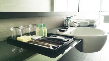 A bathroom with a black tray holding toiletries, a white sink, and a window in the background.