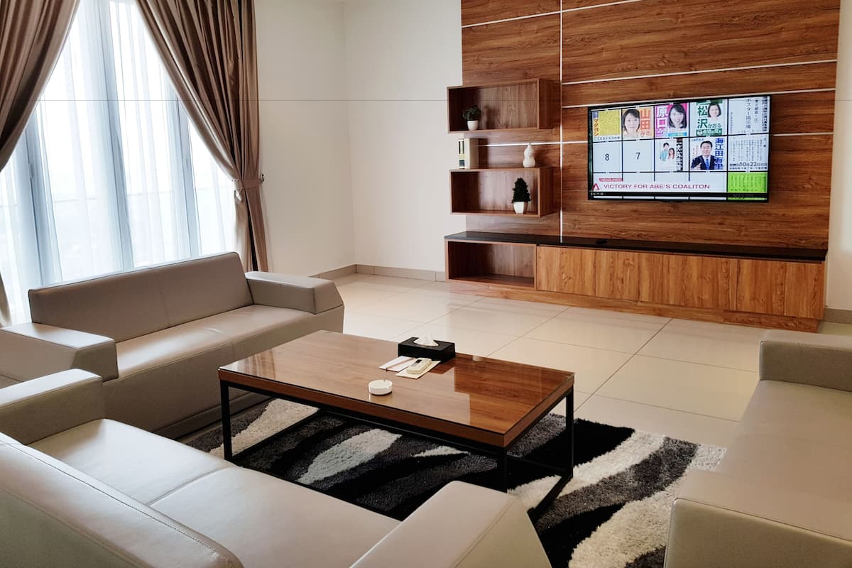 A modern living room with a sofa set, a coffee table, and a TV mounted on a wooden wall.