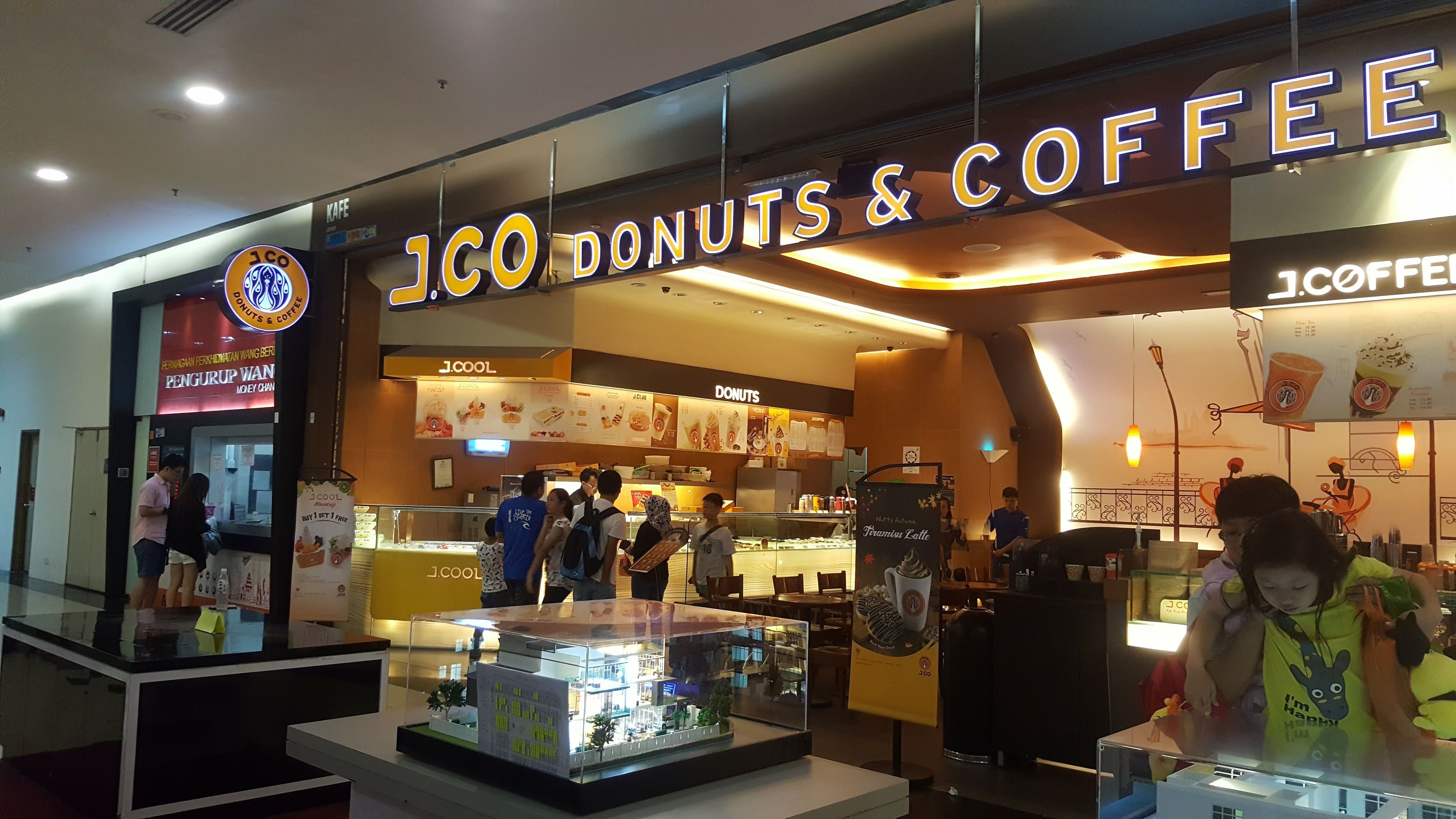 Kahvila nimeltä ’JCO Donuts & Coffee’, jossa on selkeästi näkyvillä oleva menutaulu ja vitriini, jossa on esillä leivonnaisia.