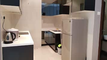 A modern kitchen with a stainless steel refrigerator, a kettle, and a sink.