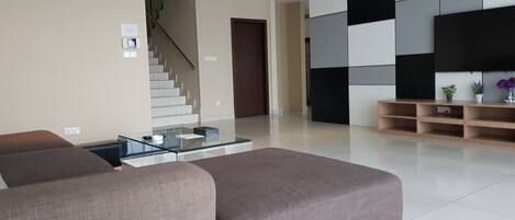 Una sala de estar moderna con un sofá, una mesa de centro de vidrio y una escalera que sube a otro nivel.