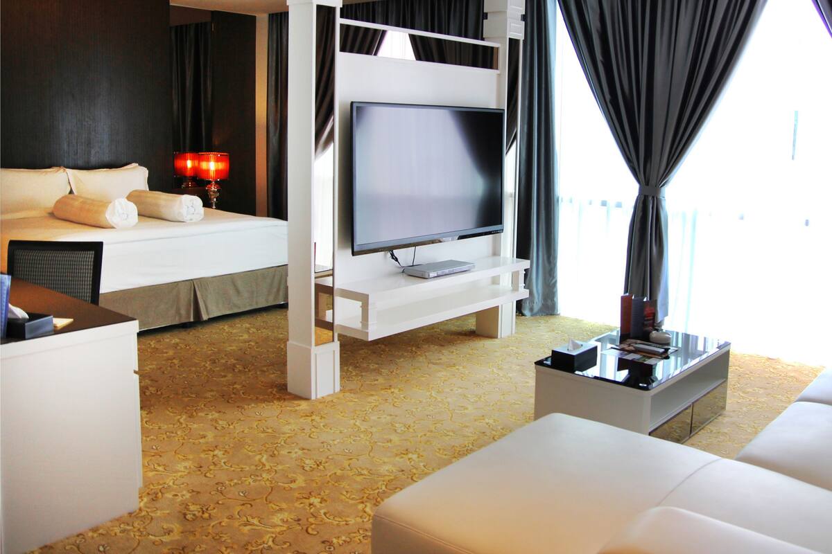 A hotel room with a bed, a TV, a sofa, and a coffee table.
