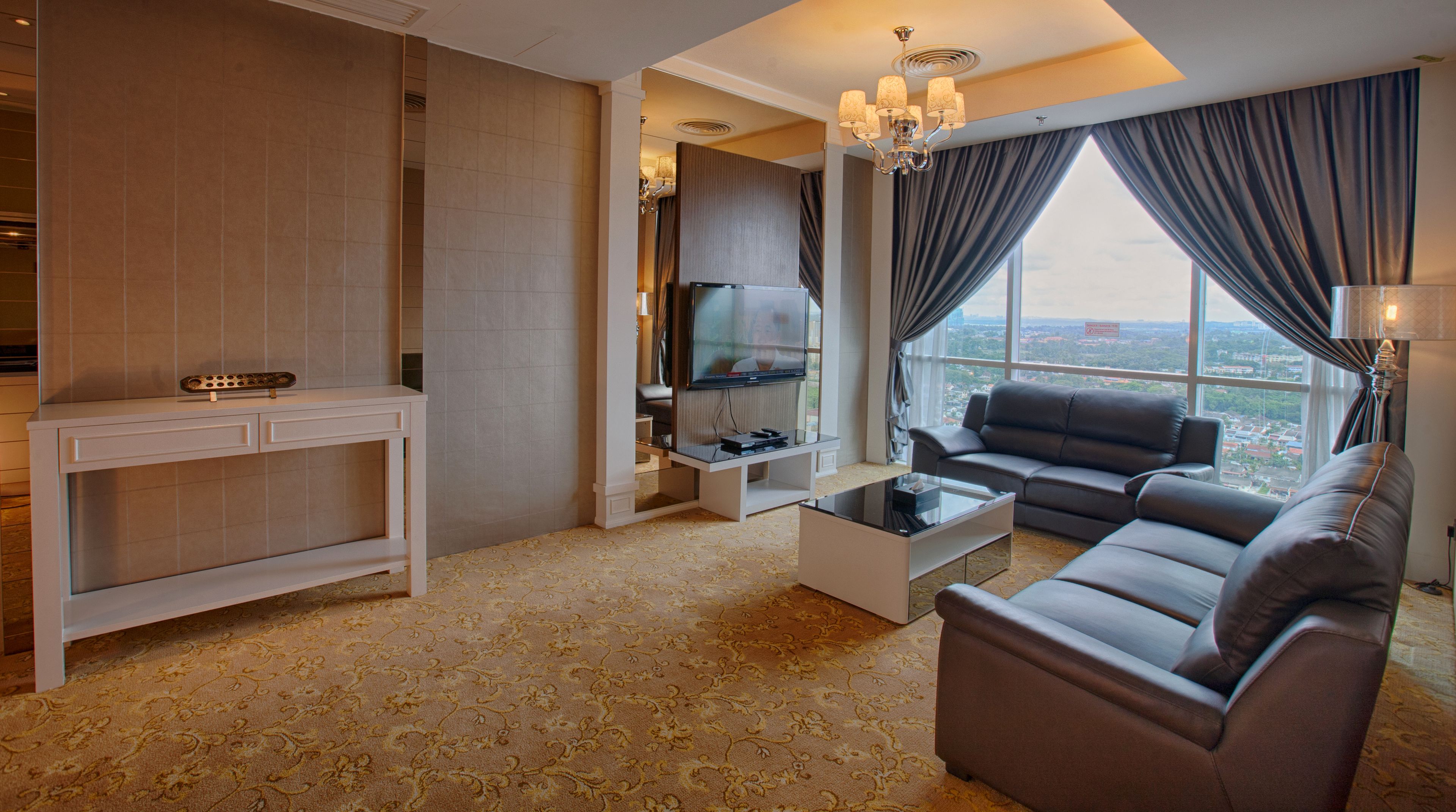 A modern living room with a sofa, a coffee table, a TV on a stand, and a view of the city through large windows.