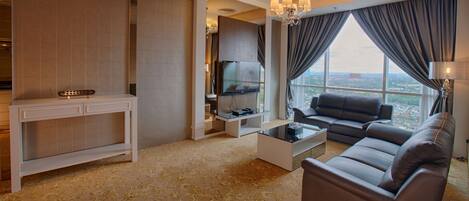 A modern living room with a sofa, a coffee table, a TV on a stand, and a view of the city through large windows.