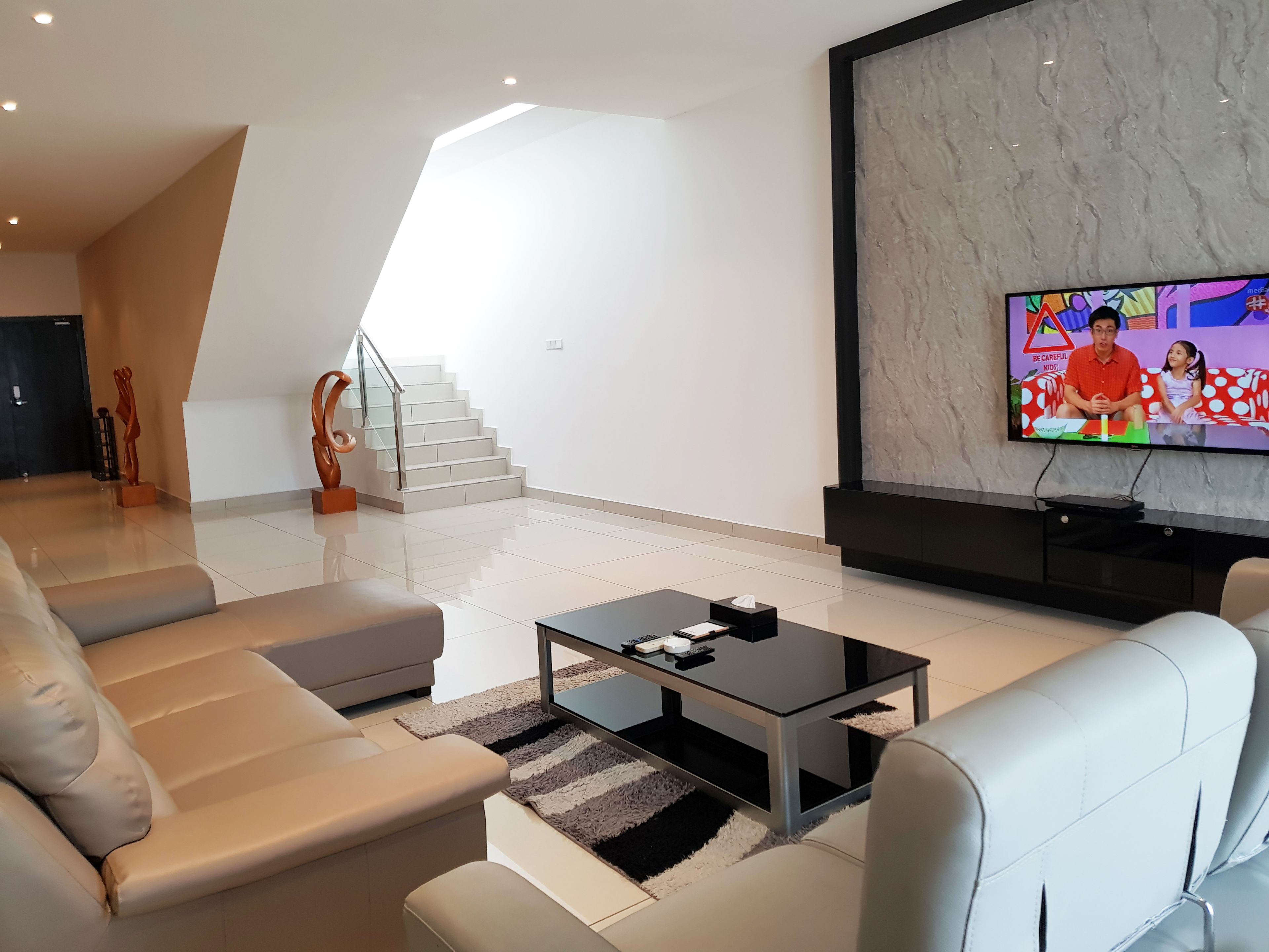 Een moderne woonkamer met een flatscreen televisie, een bank, een salontafel en een trap.
