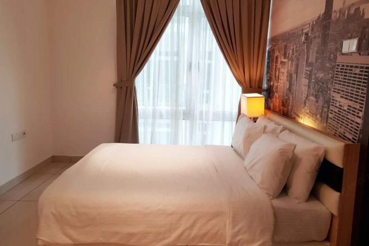 A hotel room with a bed, curtains, a lamp, and a cityscape wall.