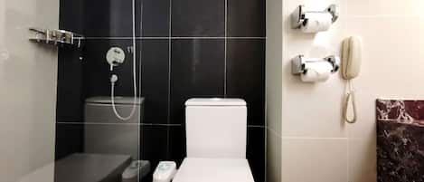 A bathroom with a toilet, a shower, and a telephone.