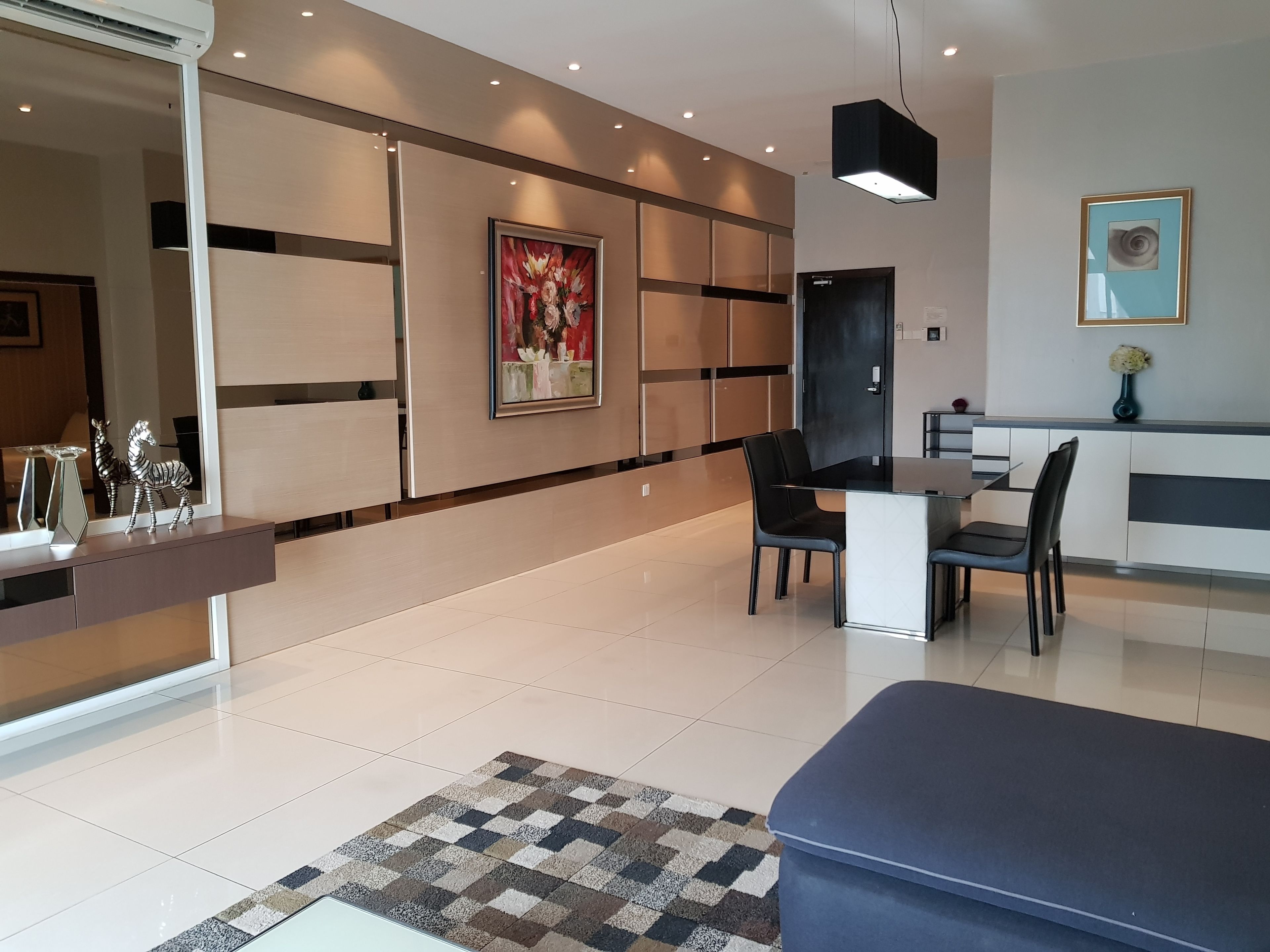 A modern living room with a dining area, featuring a large painting, a sofa, and a coffee table.
