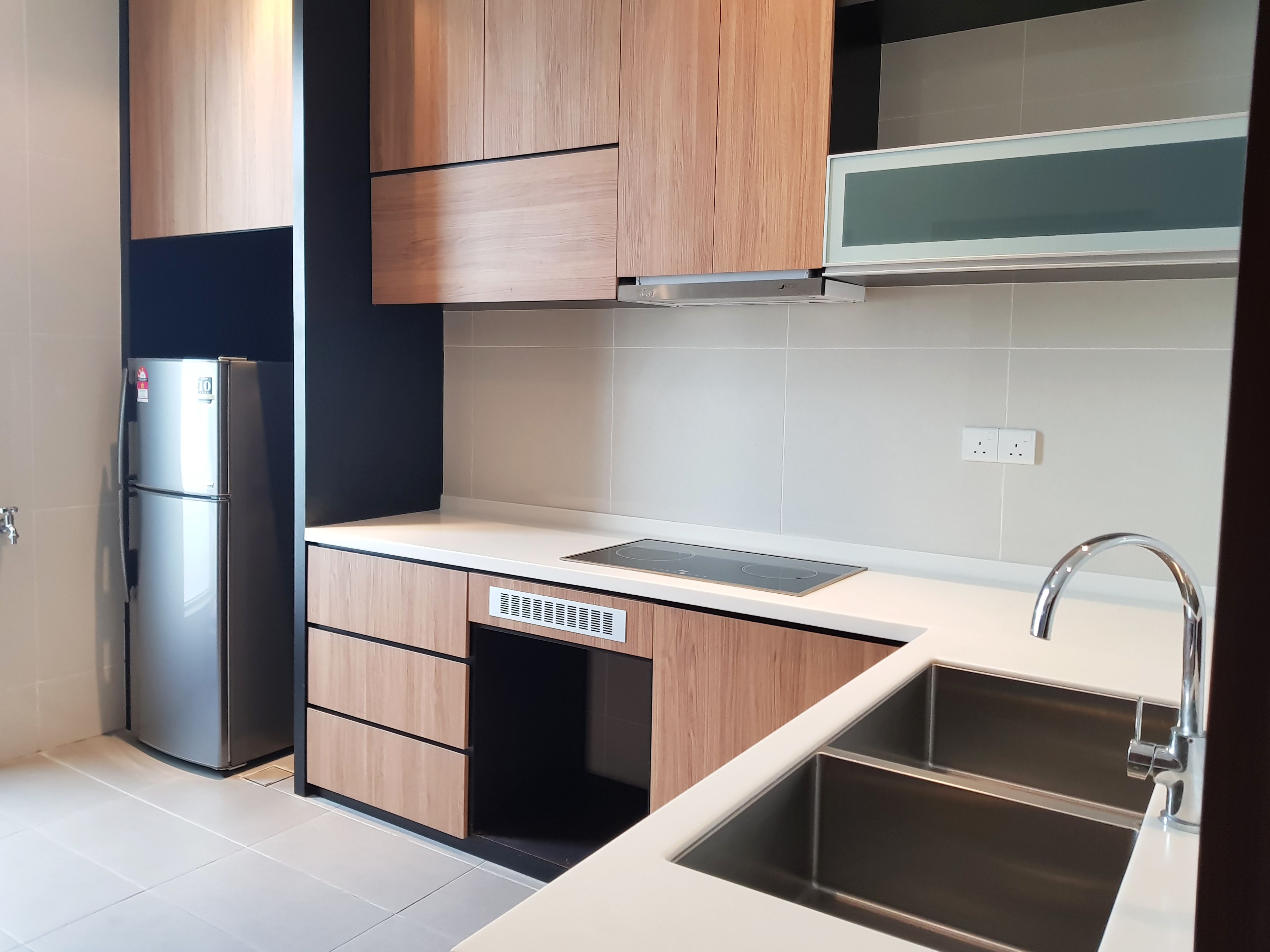 A modern kitchen with wooden cabinets, a stainless steel refrigerator, a built-in oven, and a sink with a faucet.