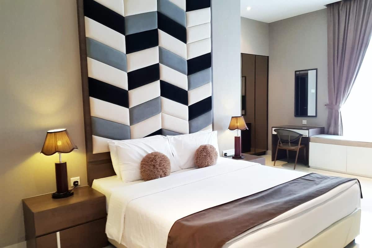A modern hotel room with a large bed, two bedside tables, a desk, and a chair.