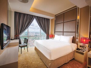 A hotel room with a large bed, a desk with a chair, a TV, and a view of the cityscape. - KSL Hotel & Resort (Johor Bahru)