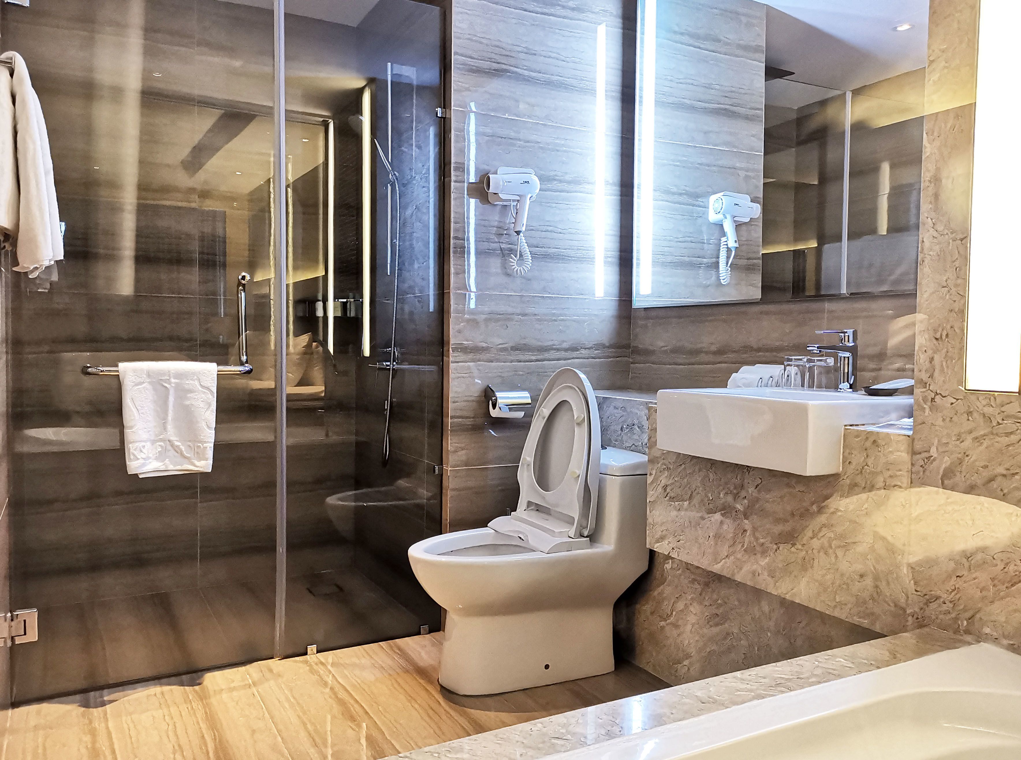 Une salle de bain moderne dotée d’une douche à parois de verre, de toilettes et d’un lavabo.