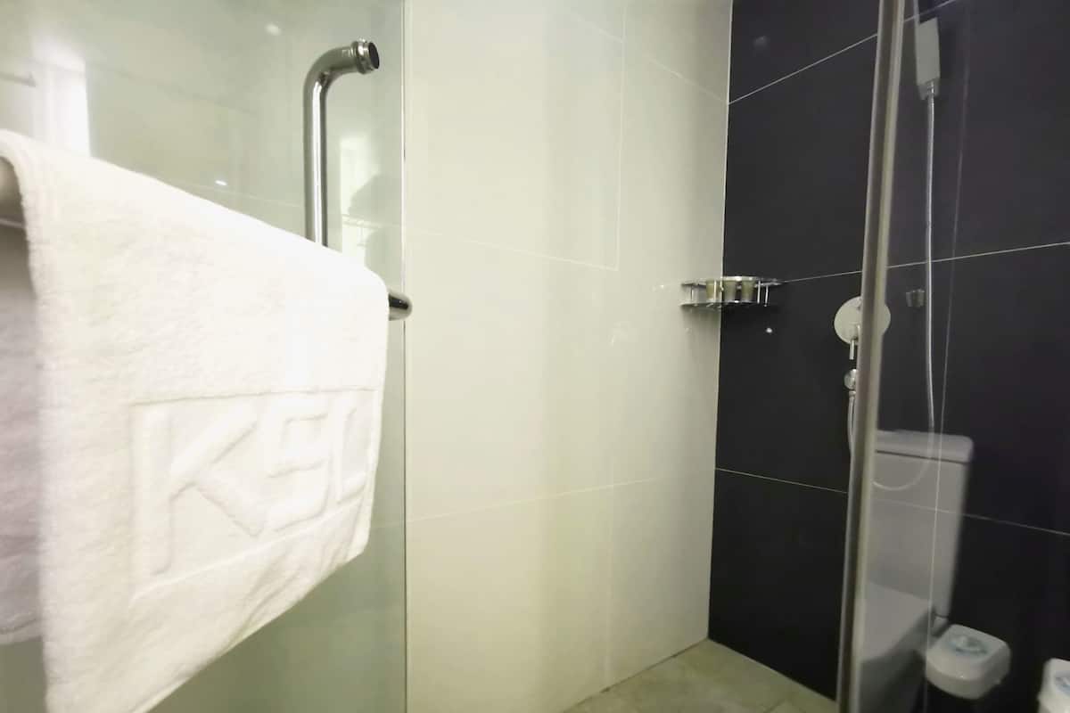 A modern bathroom with a glass shower enclosure, a white towel hanging on a rack, and a toilet.