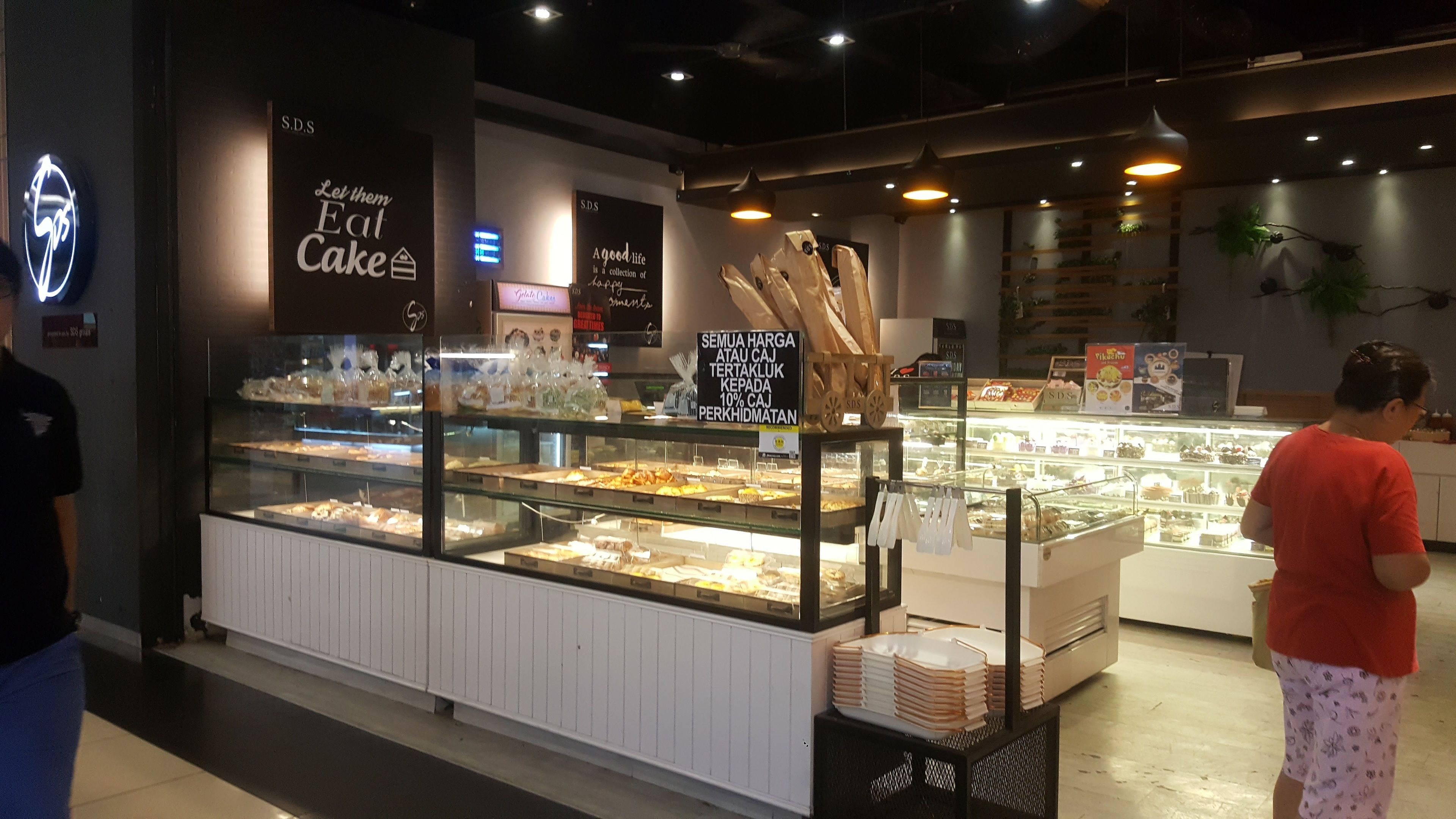 Mostrador de panadería con diversos productos horneados, un letrero que indica un descuento del 10% y un letrero de neón sobre la entrada.