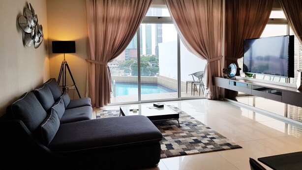 Una sala moderna con un sofá, televisor y vista a la piscina.