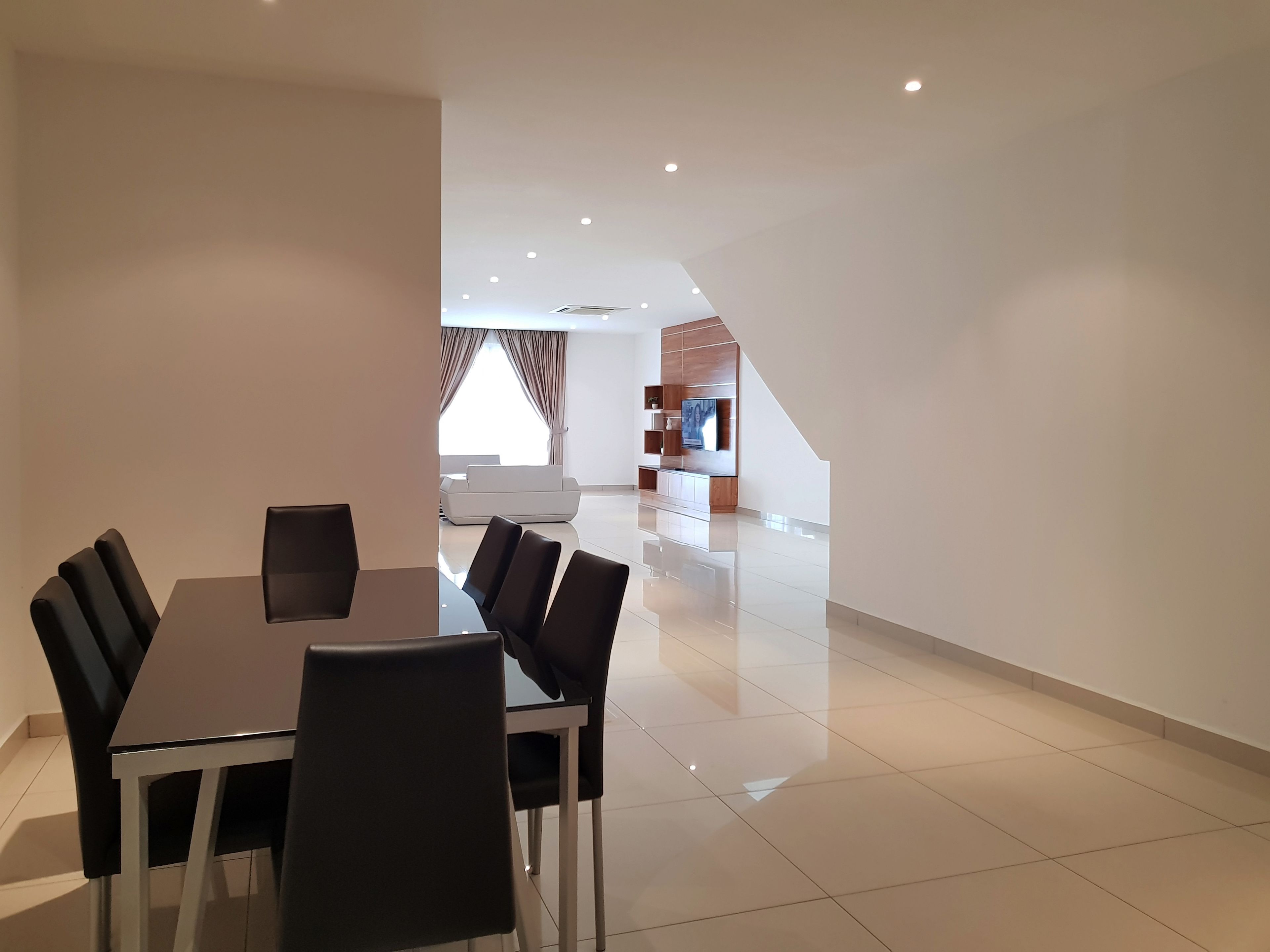 Una sala de estar moderna con comedor, que incluye una mesa grande y sillas, un sofá y un mueble empotrado para entretenimiento.