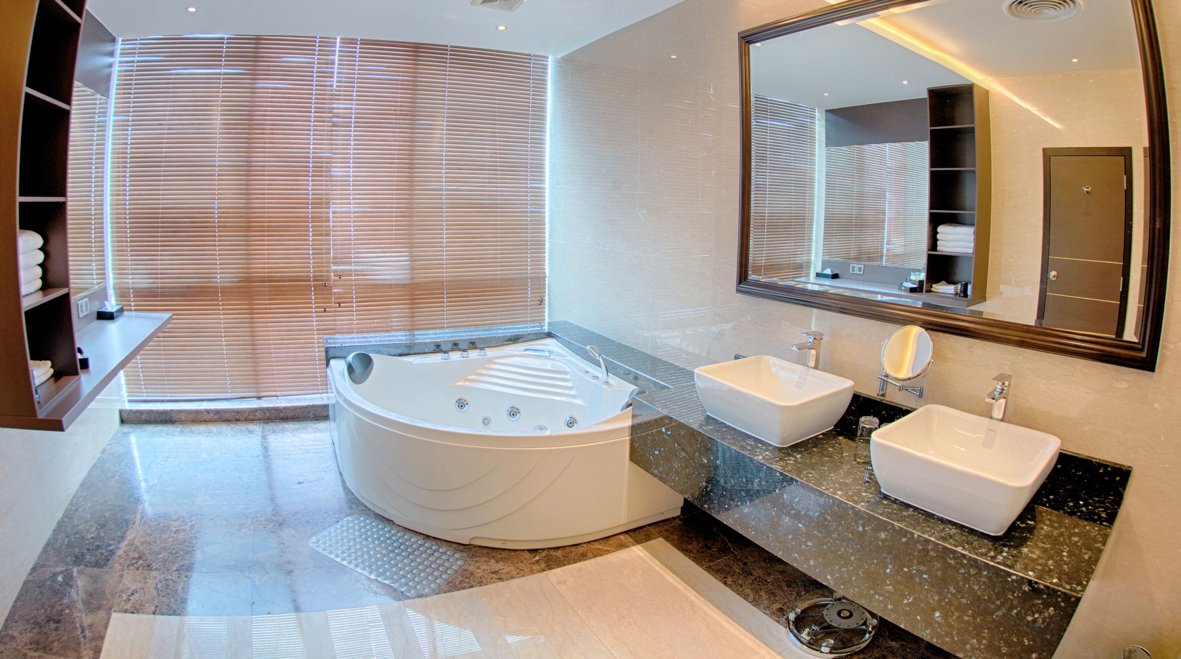 Une salle de bain moderne avec une grande baignoire sur pieds, deux lavabos et un grand miroir.