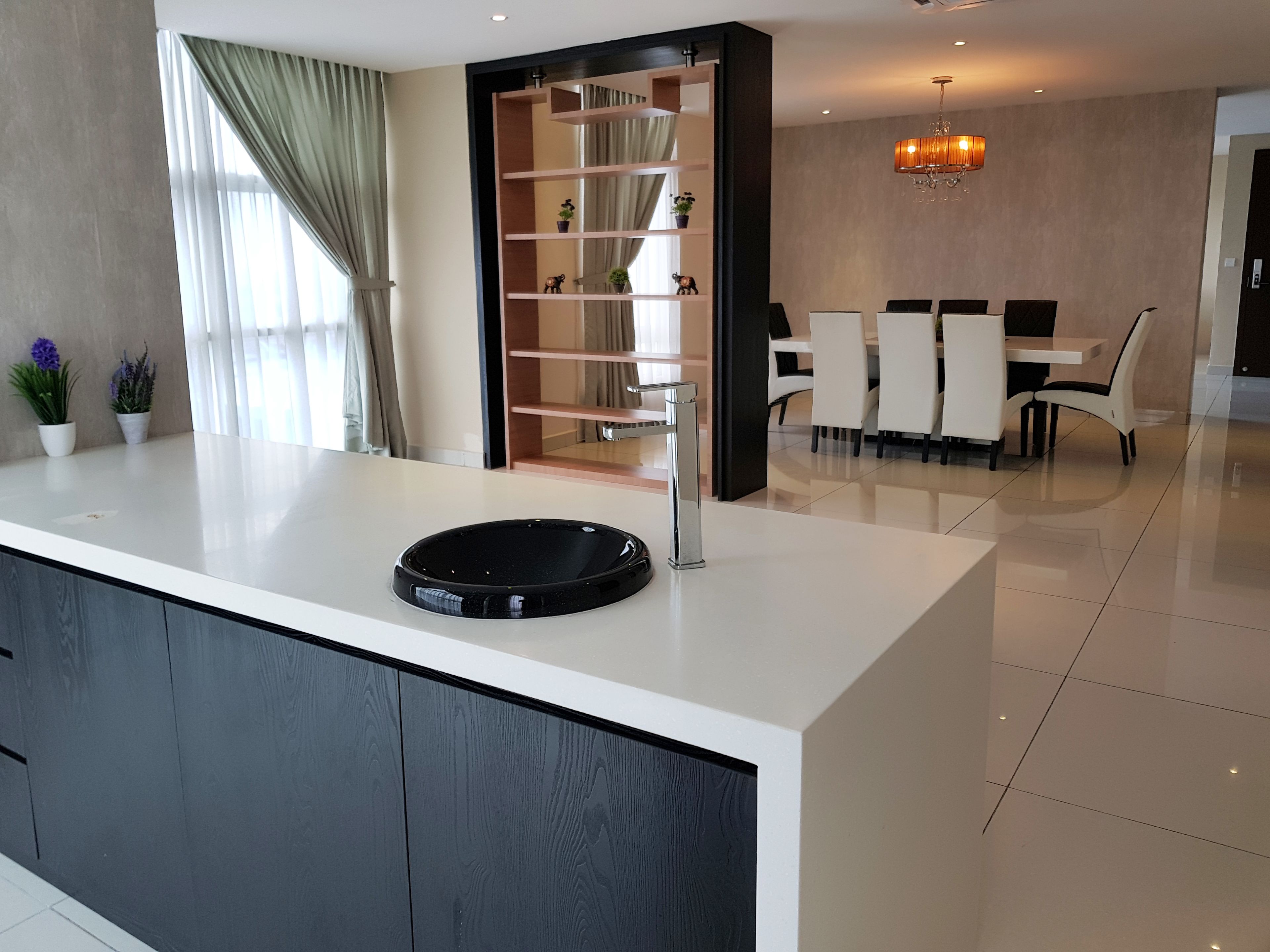 Une cuisine moderne avec un îlot central, un coin repas avec des chaises blanches et un lustre.