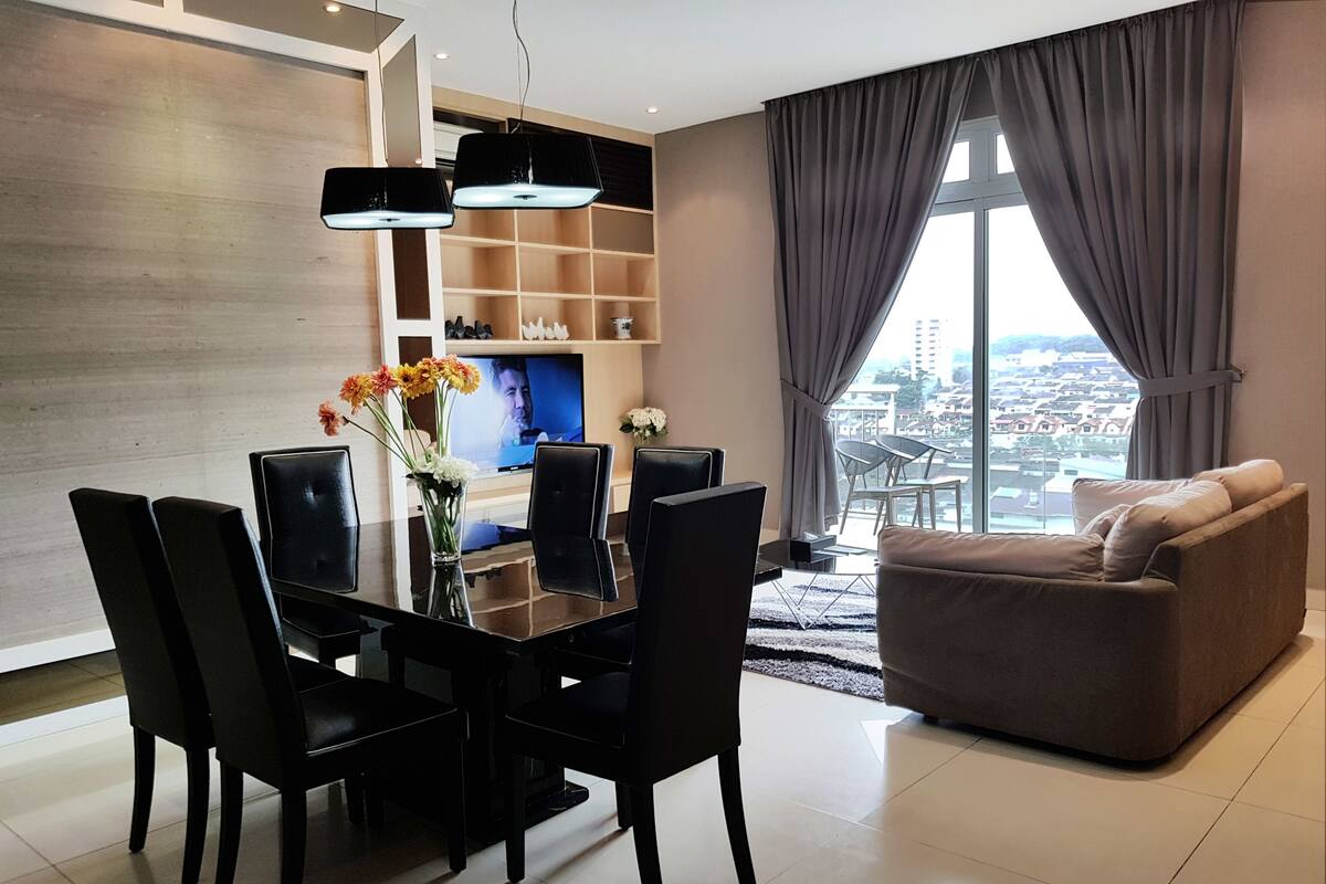 A modern living room with a dining table, chairs, a sofa, and a TV.
