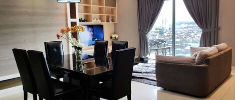 A modern living room with a dining table, chairs, a sofa, and a TV.