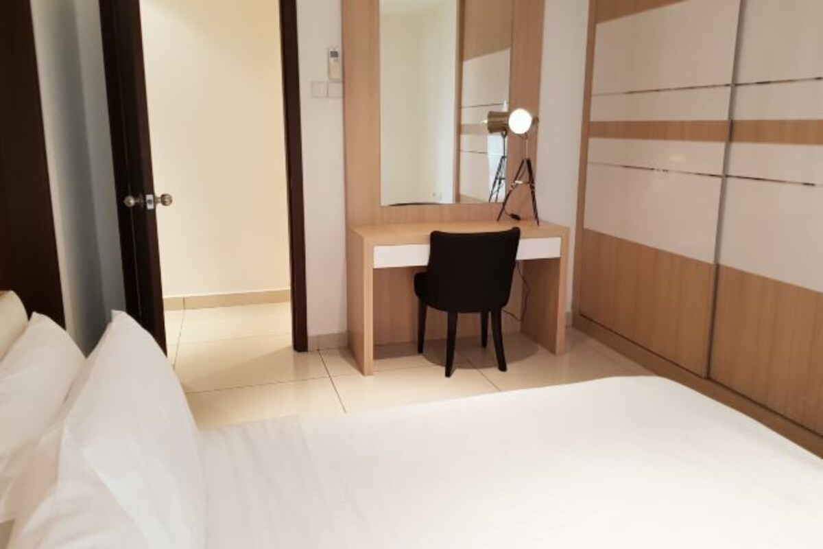 A hotel room with a bed, a desk, a chair, a mirror, and a wardrobe.